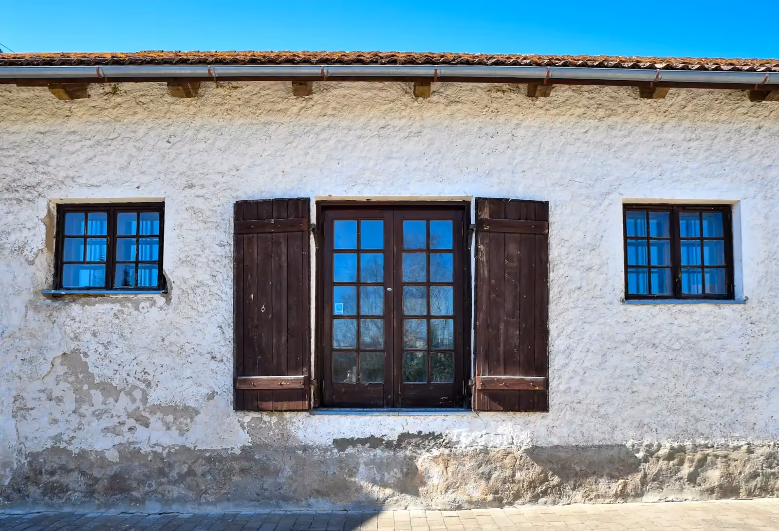 Facciata bianca con porta e scuri in legno scuro