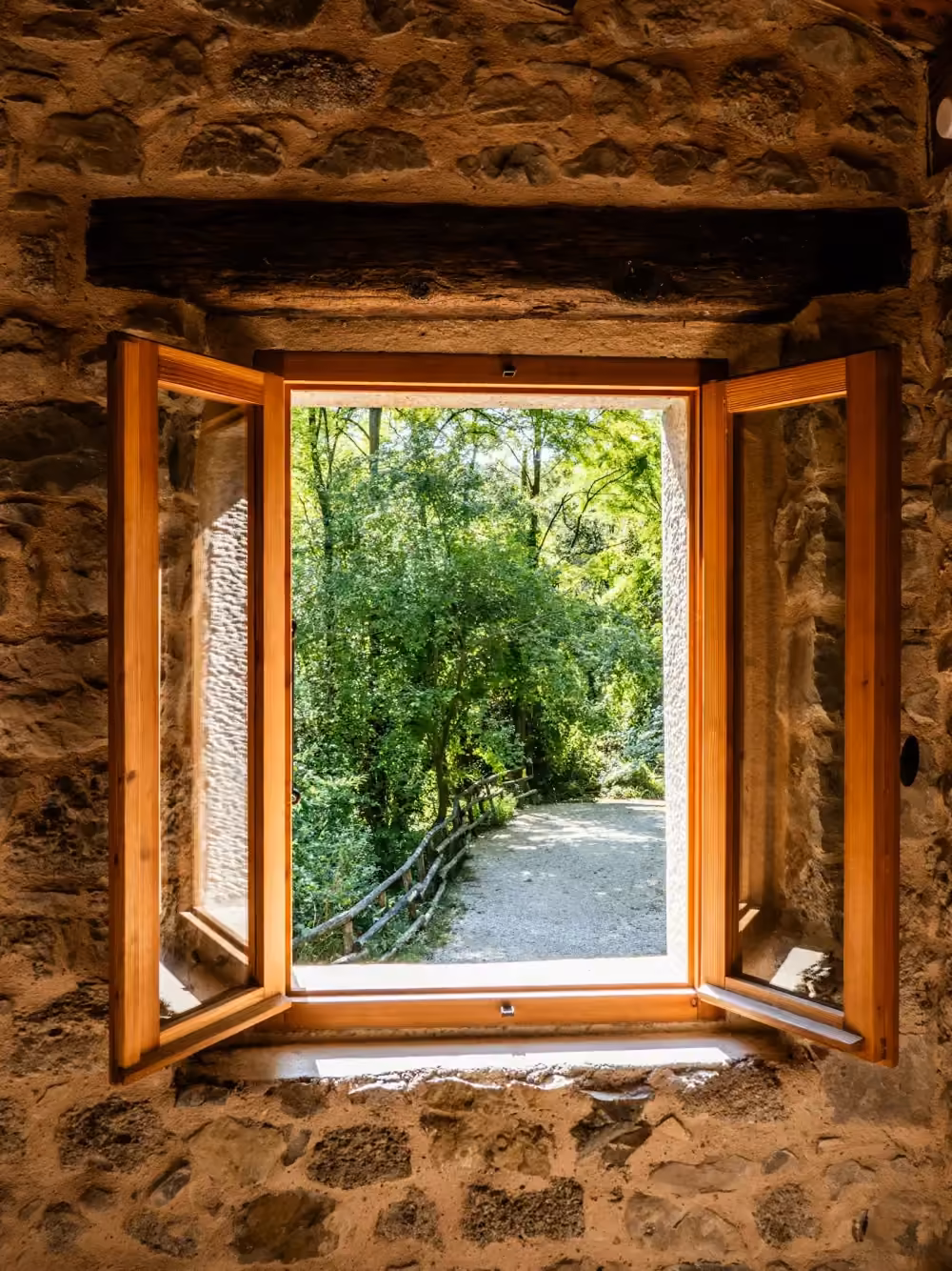 Finestra in legno a due ante aperta in un muro di pietra