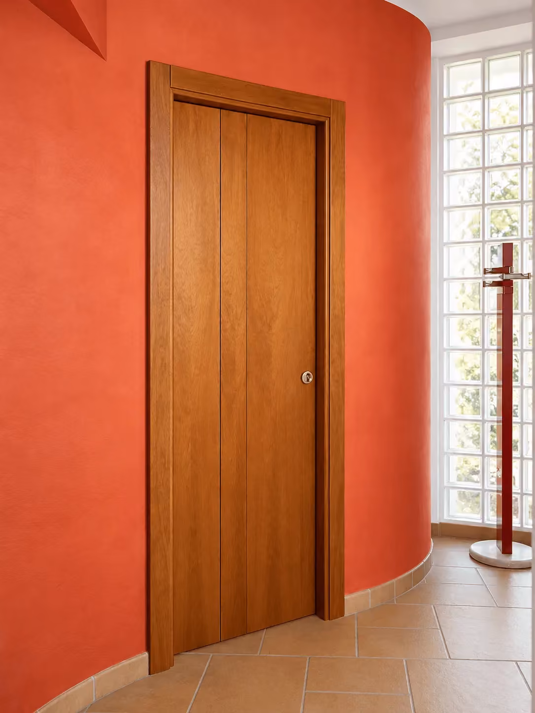 Porta per interni in ciliegio a libro, su una parete curva color terracotta