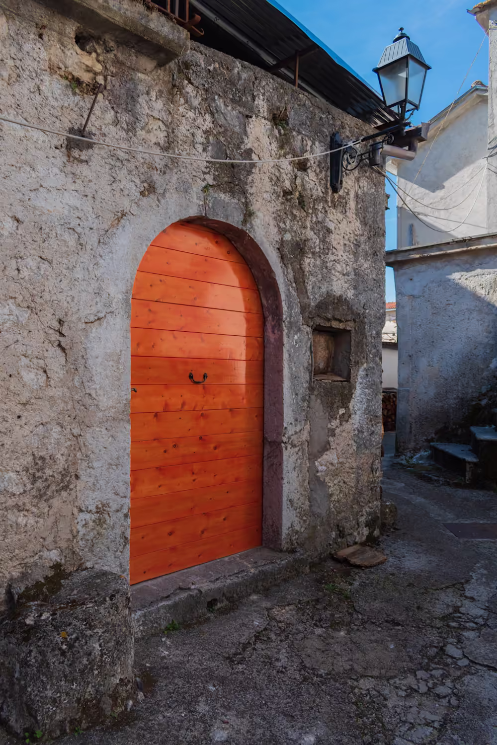 Portone in legno ad arco in un muro di pietra