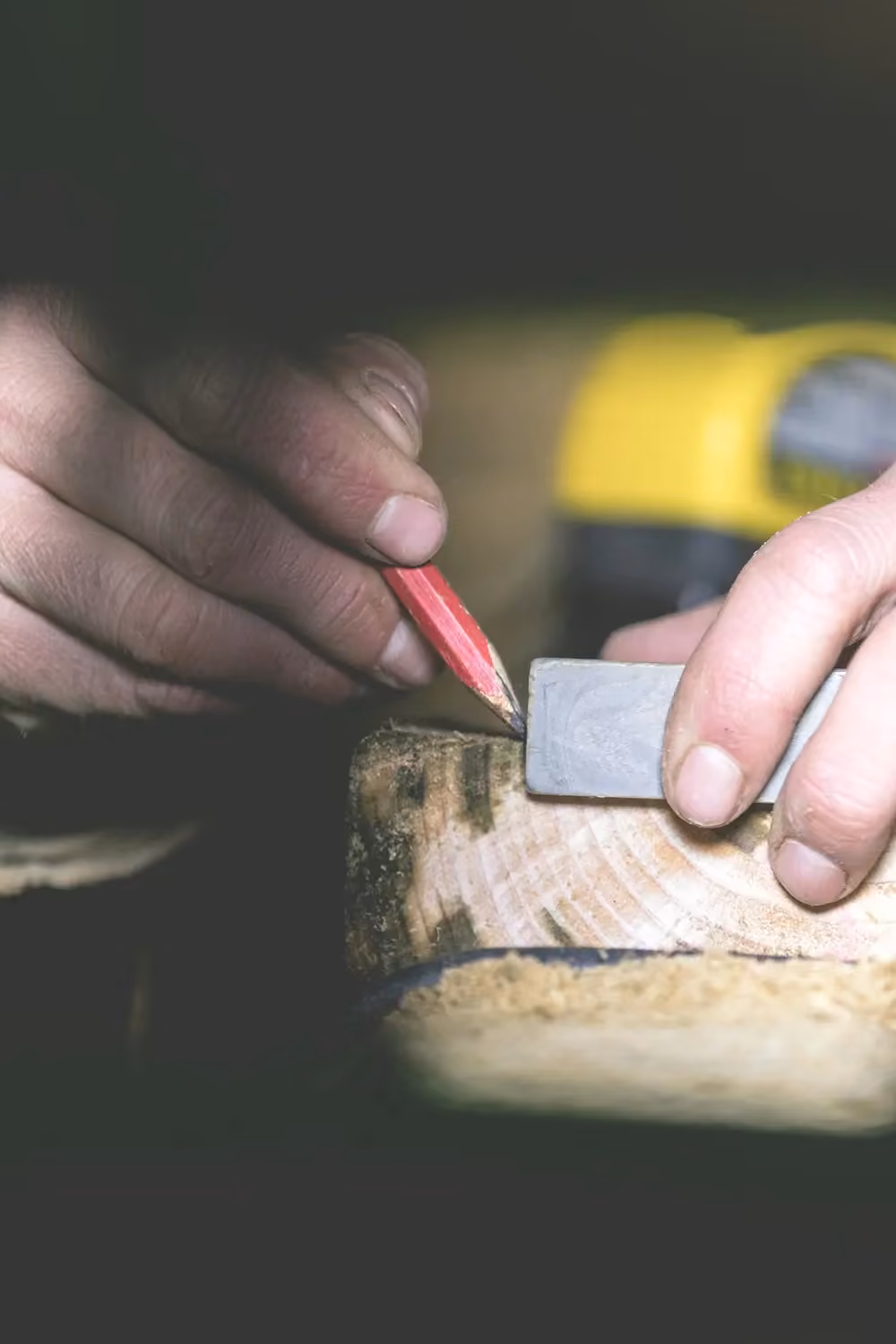 Mano che traccia una linea a matita su un pezzo di legno